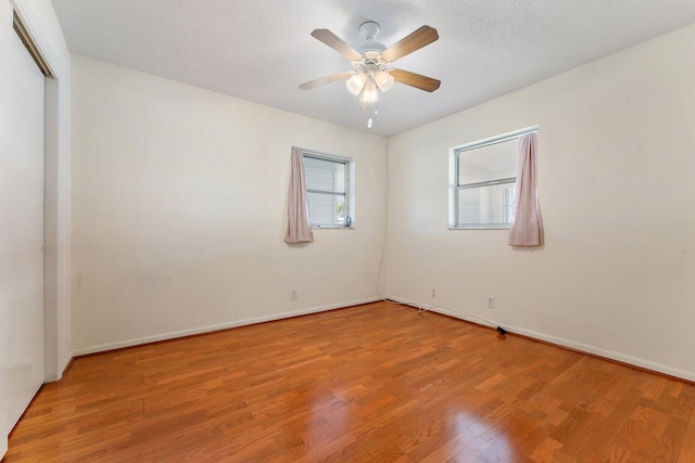 empty room featuring a textured ceiling, light hardwood / wood-style flooring, and ceiling fan