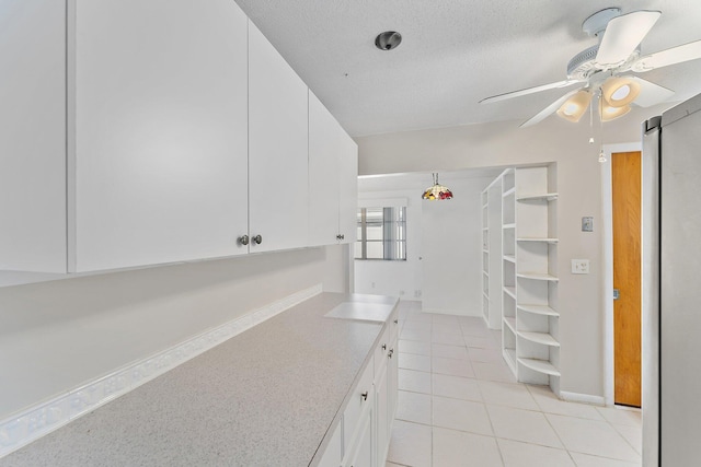 kitchen featuring white cabinets, light tile patterned floors, a textured ceiling, and ceiling fan