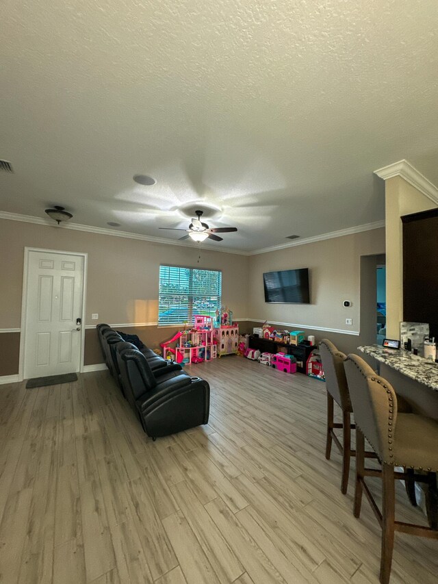 living room with a textured ceiling, ceiling fan with notable chandelier, and ornamental molding