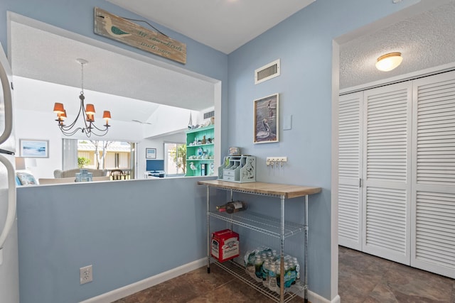 kitchen featuring decorative light fixtures, kitchen peninsula, a textured ceiling, and a chandelier