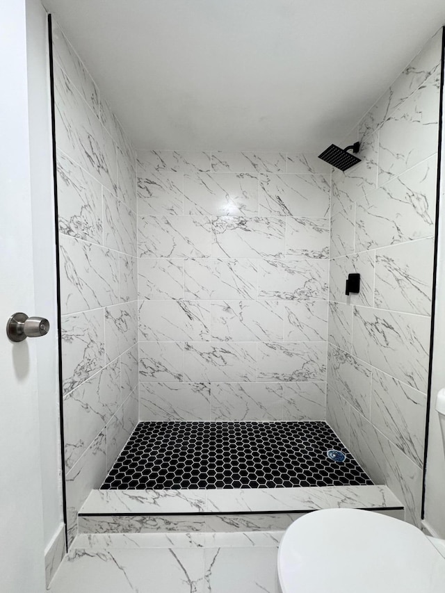 bathroom featuring a tile shower and toilet