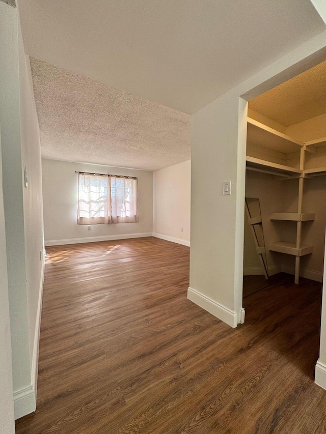 unfurnished living room featuring dark hardwood / wood-style flooring and a textured ceiling