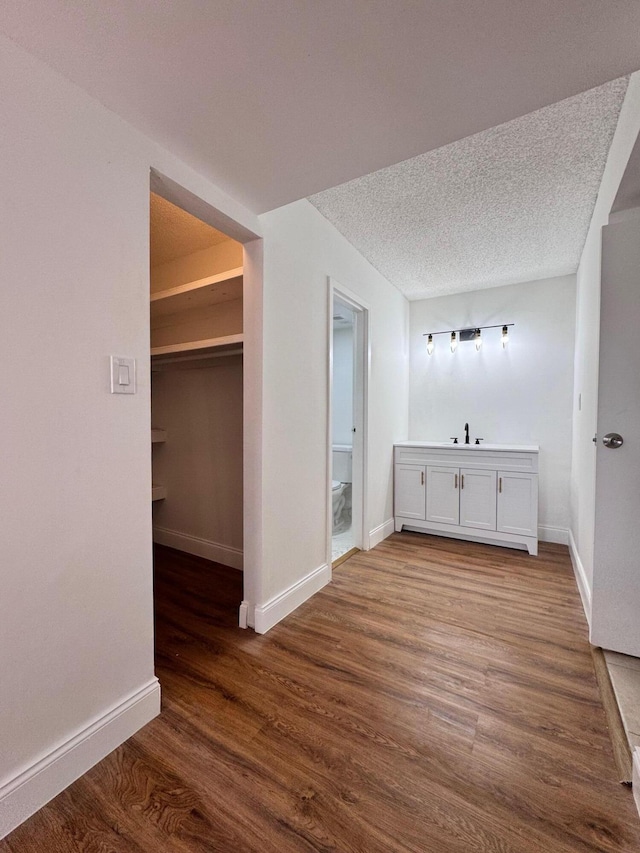 bathroom with a textured ceiling, hardwood / wood-style flooring, toilet, and sink