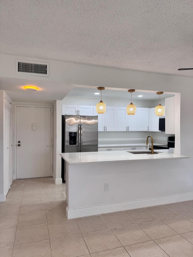 kitchen featuring pendant lighting, white cabinets, sink, stainless steel fridge, and light tile patterned flooring