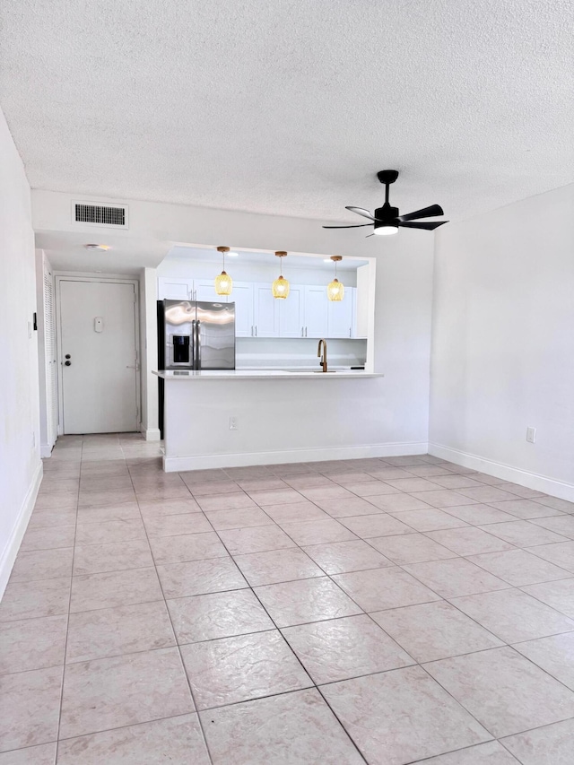 unfurnished living room featuring a textured ceiling, sink, ceiling fan, and light tile patterned flooring