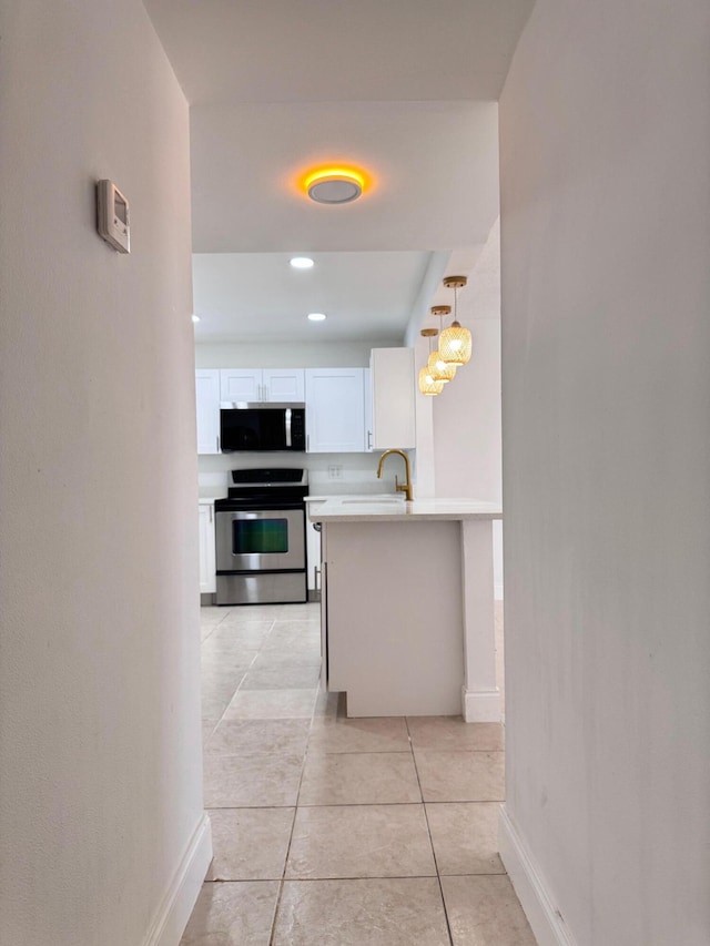 kitchen featuring white cabinets, hanging light fixtures, light tile patterned flooring, kitchen peninsula, and stainless steel appliances