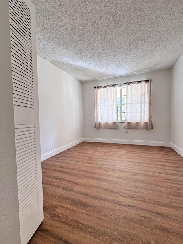 unfurnished room with a textured ceiling and hardwood / wood-style flooring