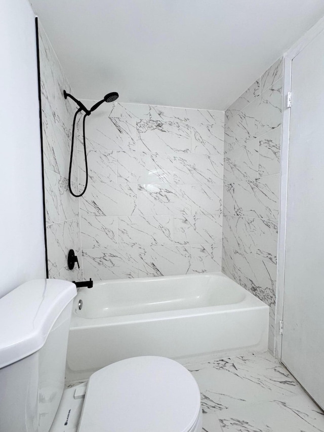 bathroom featuring tiled shower / bath combo and toilet