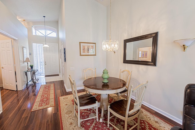 dining space with dark hardwood / wood-style flooring, a chandelier, and a high ceiling