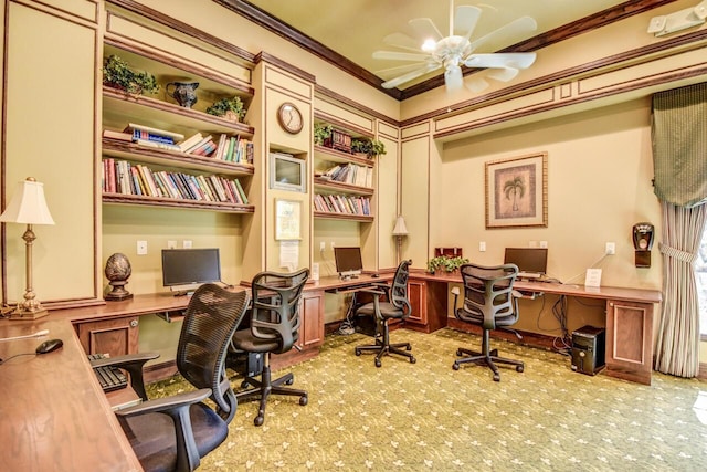 carpeted office with ceiling fan, ornamental molding, and built in desk