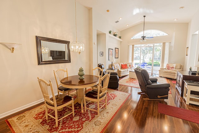 dining area with high vaulted ceiling, ceiling fan with notable chandelier, and dark hardwood / wood-style flooring