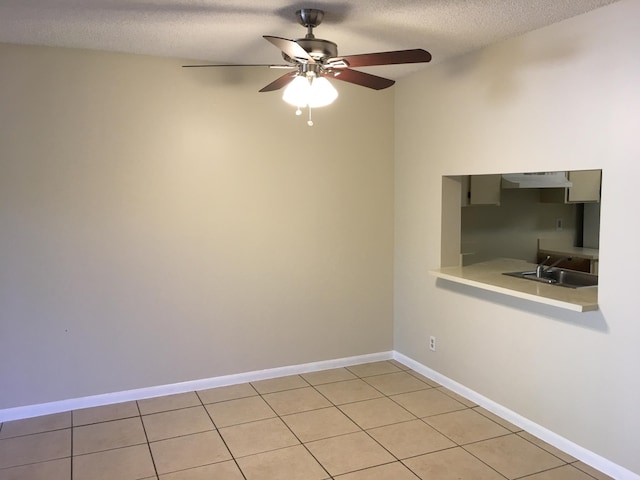 tiled spare room featuring ceiling fan, sink, and a textured ceiling