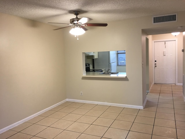 tiled empty room with a textured ceiling, ceiling fan, and sink