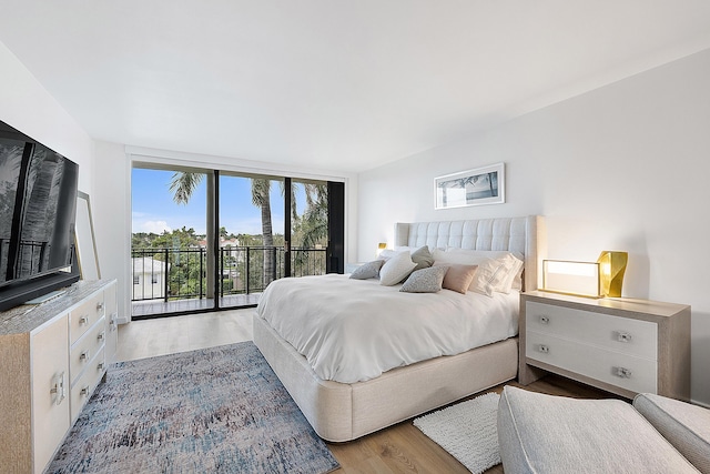 bedroom with a wall of windows, access to exterior, and light hardwood / wood-style floors