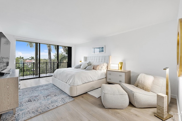 bedroom featuring access to outside, light wood-type flooring, and floor to ceiling windows