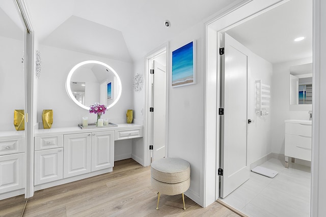 bathroom featuring hardwood / wood-style floors, vaulted ceiling, and vanity