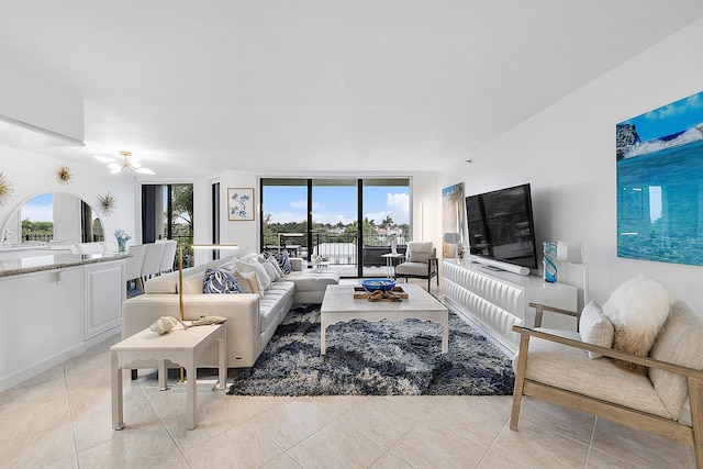 tiled living room featuring ceiling fan and expansive windows