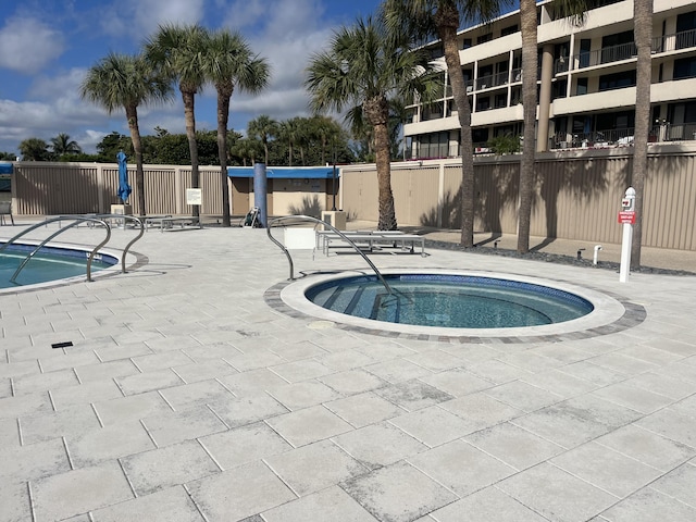 view of pool with a hot tub and a patio