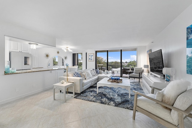 living room with a wall of windows, ceiling fan, and light tile patterned floors