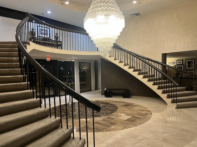 stairway featuring a notable chandelier and a towering ceiling