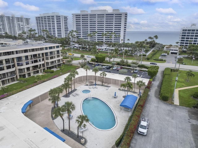 view of pool featuring a community hot tub, a water view, and a patio area