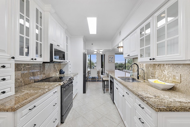 kitchen with stainless steel appliances, stone countertops, white cabinets, and sink