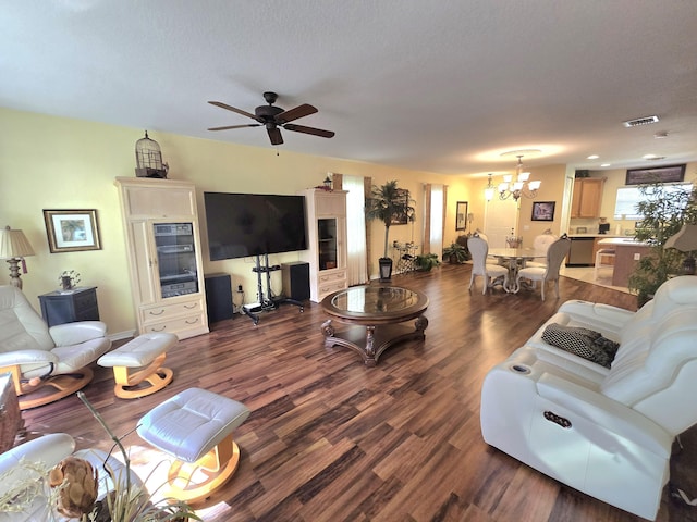 living room with ceiling fan with notable chandelier, dark hardwood / wood-style flooring, and a textured ceiling