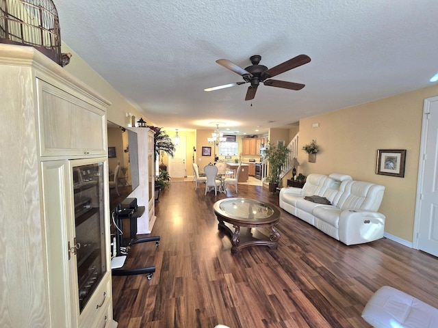 living room with ceiling fan with notable chandelier, dark hardwood / wood-style flooring, and a textured ceiling