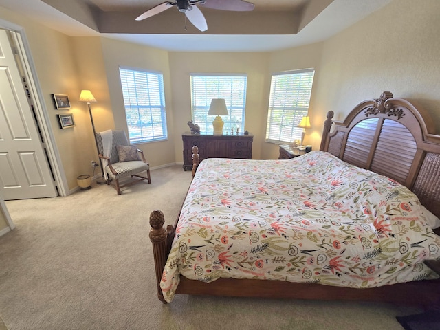 bedroom featuring ceiling fan, a raised ceiling, and light carpet