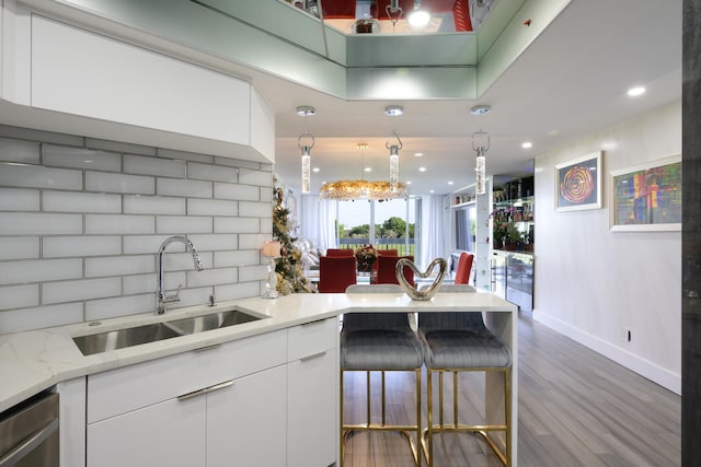 kitchen featuring tasteful backsplash, stainless steel dishwasher, sink, wood-type flooring, and white cabinets