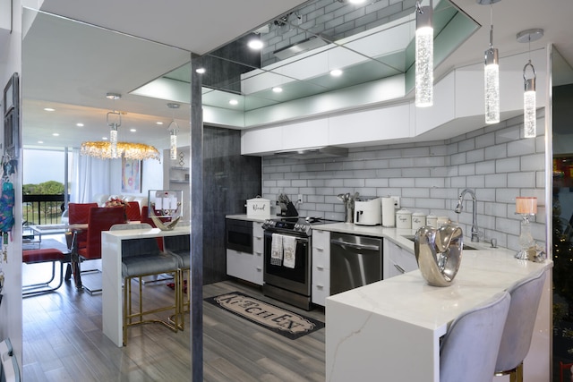 kitchen featuring white cabinets, appliances with stainless steel finishes, light stone countertops, and hanging light fixtures