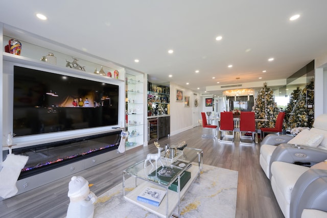 living room with hardwood / wood-style flooring, built in features, wine cooler, and bar area