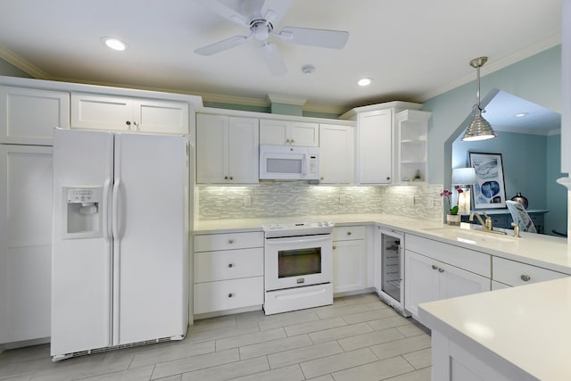 kitchen featuring white appliances, backsplash, sink, hanging light fixtures, and white cabinetry