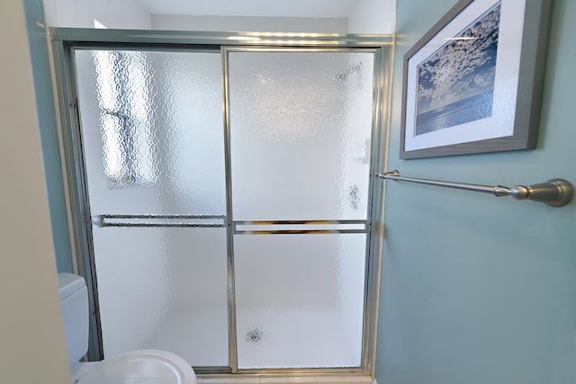 bathroom featuring toilet and a shower with shower door