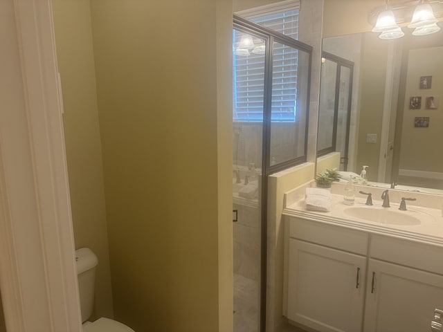 bathroom with toilet, vanity, an inviting chandelier, and walk in shower