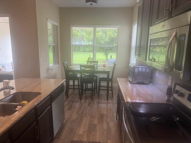 kitchen with dark hardwood / wood-style flooring, dark brown cabinetry, sink, and appliances with stainless steel finishes