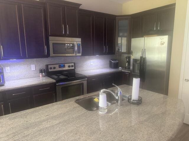 kitchen with light stone counters, sink, appliances with stainless steel finishes, and tasteful backsplash