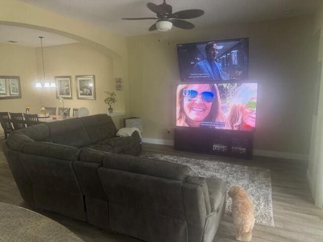 living room with ceiling fan with notable chandelier and hardwood / wood-style flooring