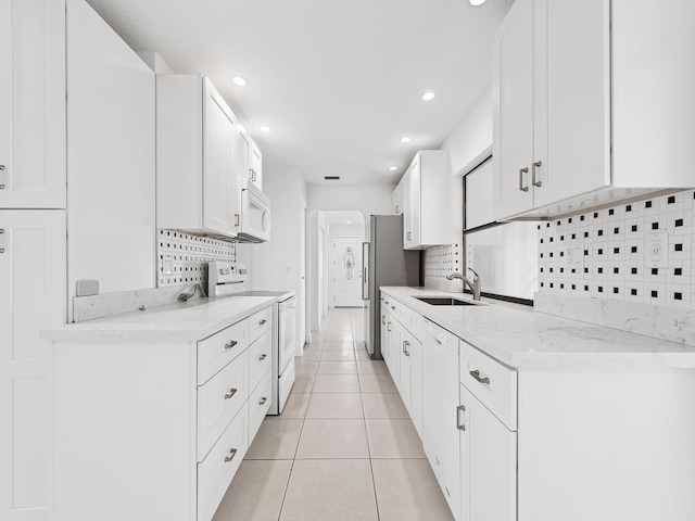 kitchen with white appliances, tasteful backsplash, white cabinets, light tile patterned flooring, and sink