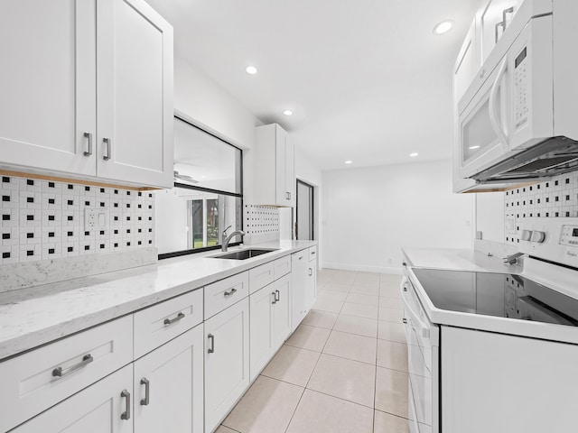 kitchen featuring white appliances, white cabinetry, backsplash, and sink