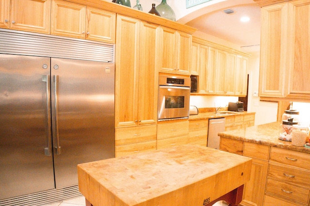 12858 153rd Ct N, Jupiter, FL 33478 - kitchen with arched walkways, light stone counters, light brown cabinetry, appliances with stainless steel finishes, and a sink