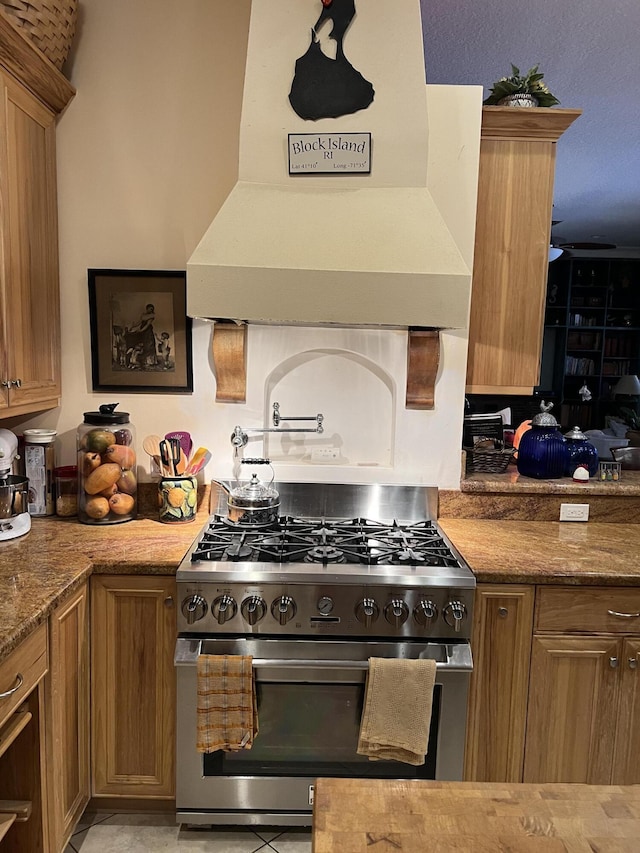 kitchen featuring dark stone countertops, high end stainless steel range, and custom exhaust hood