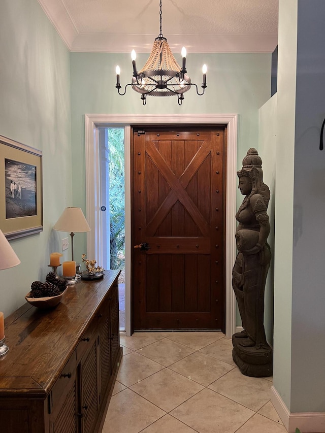 tiled entrance foyer with ornamental molding and an inviting chandelier