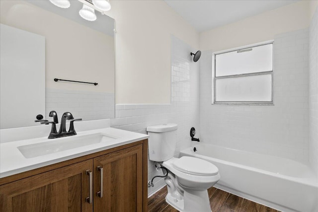 full bathroom featuring toilet, vanity, tile walls, and tiled shower / bath combo