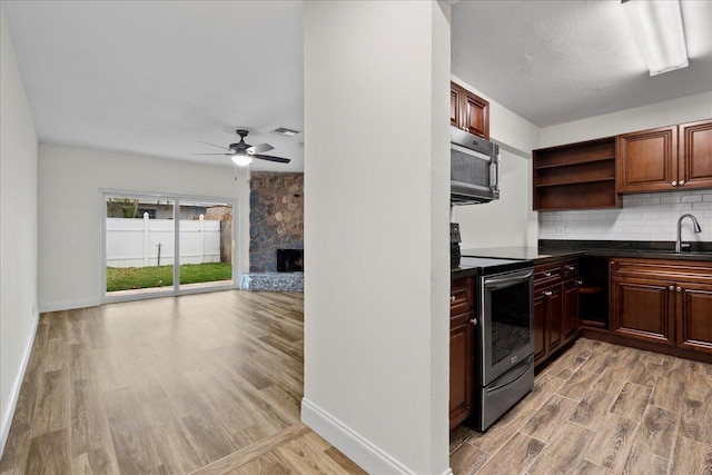 kitchen featuring decorative backsplash, ceiling fan, light hardwood / wood-style flooring, and appliances with stainless steel finishes