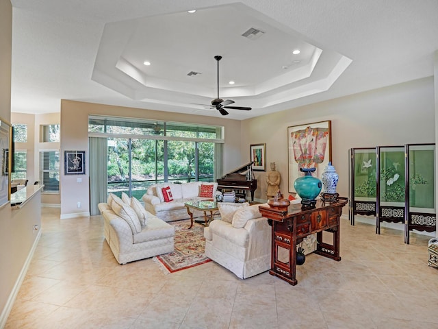 tiled living room featuring ceiling fan and a raised ceiling