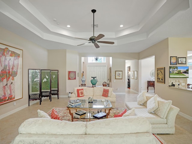 living room featuring light tile patterned floors, a raised ceiling, ceiling fan, and a high ceiling