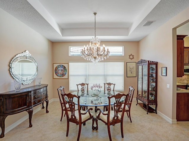 dining area with a tray ceiling, light tile patterned floors, and a notable chandelier