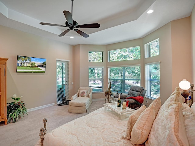 bedroom with ceiling fan, light carpet, and a tray ceiling