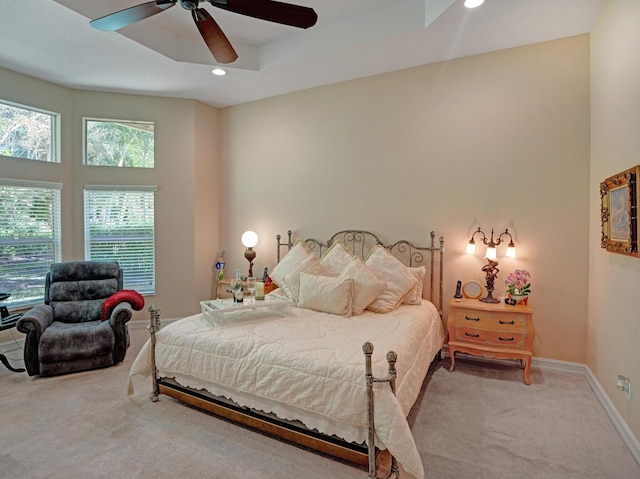 carpeted bedroom featuring a tray ceiling and ceiling fan